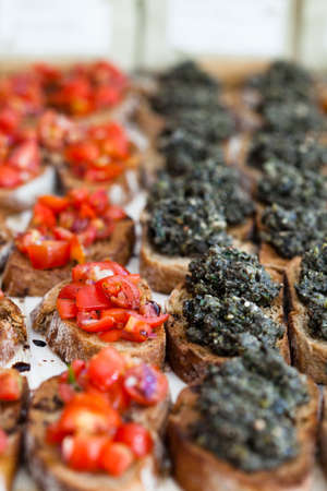 Closeup of bruschetta appetizers with savoury paste and tomato toppings presented in rowsの写真素材