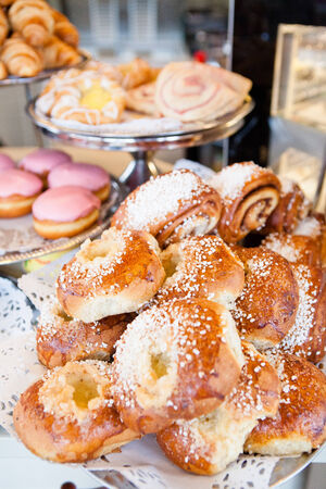 Closeup of mix of various sweet buns and donuts and croissants on display trays at cafeの写真素材