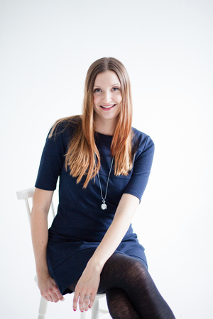 Studio portrait of happy smiling attractive woman wearing blue blouse and sitting in chairの写真素材