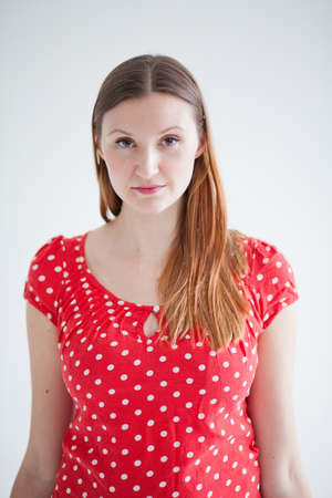 Studio portrait of thoughtful looking attractive woman wearing red spotty blouseの写真素材