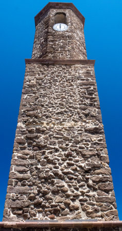high tower made of stones with clock in the middleの写真素材