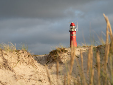 Red Lighthouse at Schiermonnikoog. Noordertoren. with beautiful scenery, lights and heavy sky in the dunesの写真素材