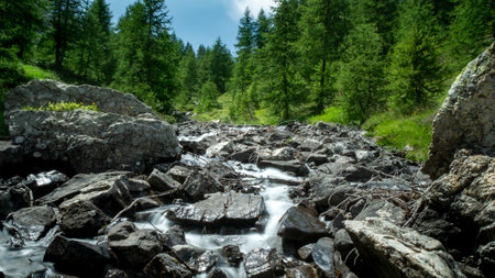 Blue water of mountain river flowing from the peaks, long exposure, National park Ecrins