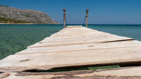 Perspective view of a wooden pier on the seashore with clear blue seaの写真素材