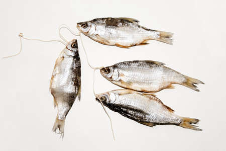 Dried fish on the table. Salty dry river fish on a white background. Dead dry salty fish - snack to beer. Isolated on white. .の写真素材