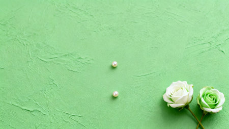 white rose and pearls on green background. flat lay, top viewの素材