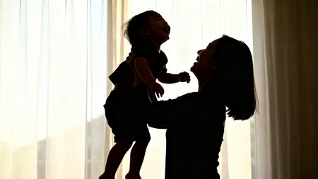 Silhouette of mother and little daughter playing together at home.の素材