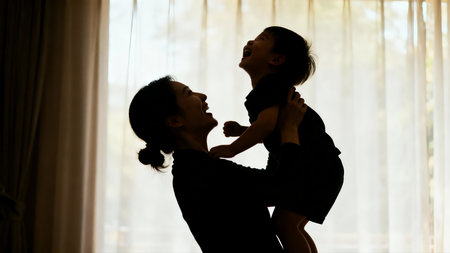 Silhouette of happy mother and daughter playing together at home.の素材