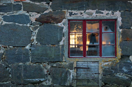 Frost on old cowshed window. Winter sun is shining through the windows