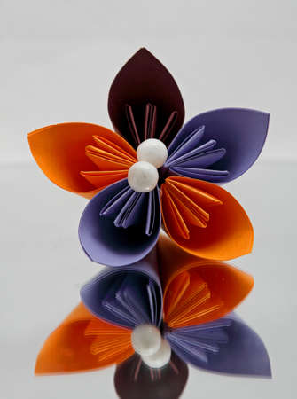 Beautiful  colourful origami flower with decoration on a mirror with white backgroundの写真素材