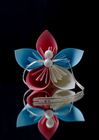 Beautiful red and blue origami flower and pearls on a black backgroundの写真素材