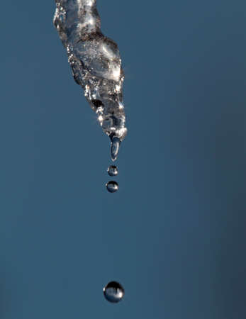 Icicle melts and water is dropping down on a bright spring dayの写真素材