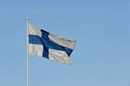 Finnish flag waving in the air against the blue skyの写真素材