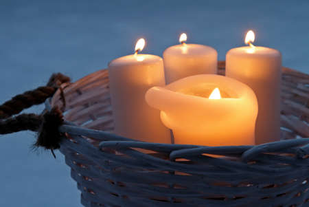 White candles burning outdoors in a rattan basketの写真素材