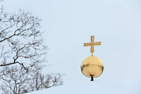 Shiny, gilded and religious symbol with small skull on the roof of a tombの写真素材
