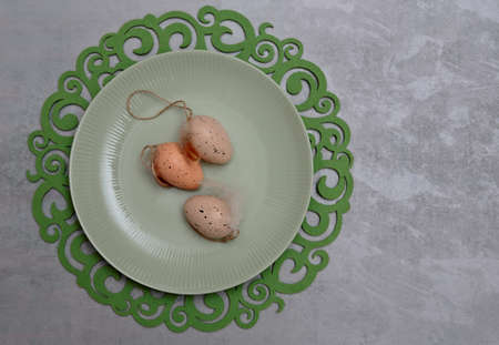 Three Easter eggs on a greenish plate and decorative tabletの写真素材