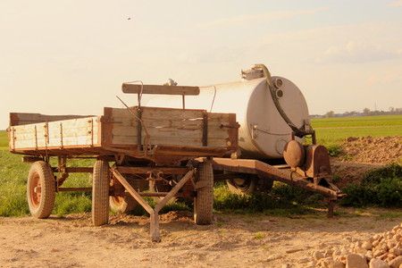Old tank vacuum truck and an old trailer stand on a rural field in spring.の写真素材