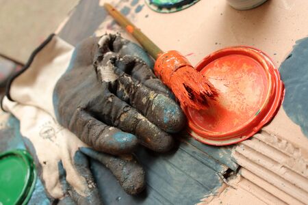 Old gloves, brush with paint and caps on the cardboard backing.の写真素材