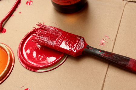 Brushes and caps dipped in colored paint lie on the cardboard backing.の写真素材