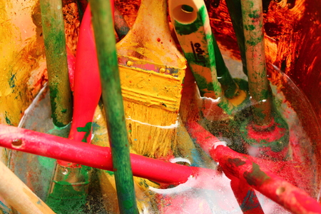 A bucket of water and a few brushes with colorful paint.の写真素材