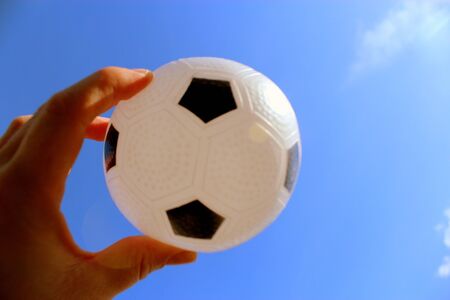 Hand is holding the ball on the background of the sky.の写真素材