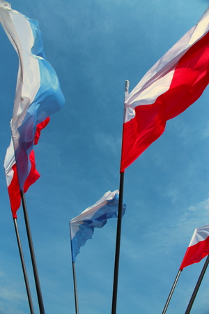 Polish flags and Marian flapping in the wind on blue sky background.の写真素材