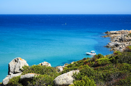 Boat in a bay with blue sea in Chia, Sardinia, Italyの写真素材