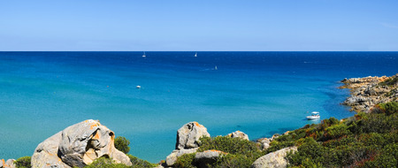 Boat in a bay with blue sea in Chia, Sardinia, Italyの写真素材