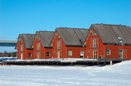 Red houses along the frozen river in Umea, north of Swedenの写真素材