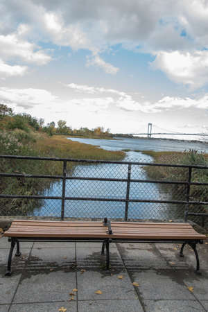 Wooden bench on the embankment of the river in the autumnの写真素材