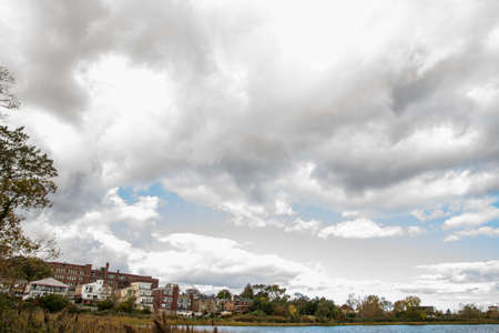 A view of a city from the shore of a lake under a cloudy sky.の写真素材