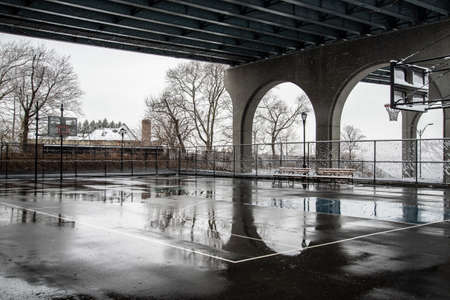 A vertical shot of a basketball court under a bridge in the cityの写真素材