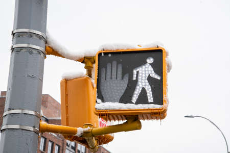 Traffic light with a pedestrian crossing sign in a snowy city.の写真素材