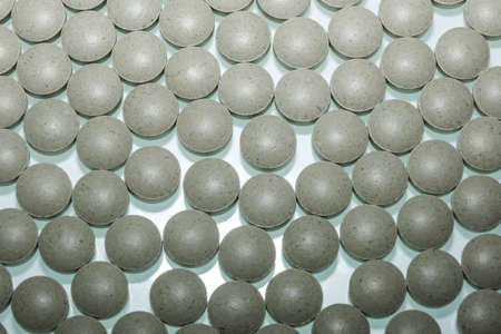 Close-up of a lot of gray capsules on a blue backgroundの写真素材