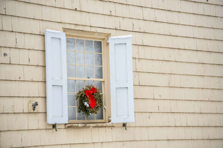Christmas wreath on the window of a house with white shuttersの写真素材