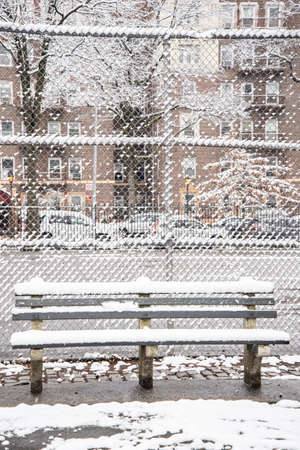 Park bench covered with snow on a winter day in the city.の写真素材