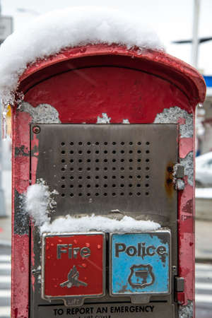 Red emergency call box with snow on the street in the city.の写真素材