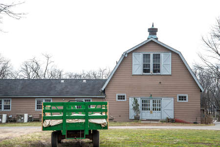 Old wooden farm house with a green trailer full of hay in the countrysideの写真素材