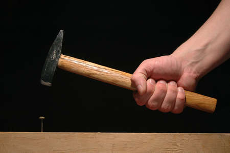 Man’s hand holding hammer isolated on black background