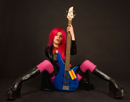Attractive rock girl in crazy outfit sitting with bass guitarの写真素材