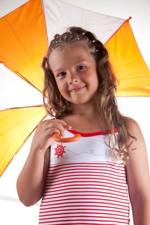 Little girl wearing summer dress and holding umbrella, studio shot の写真素材