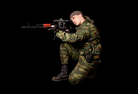 Soldier in uniform with rifle, isolated on black background の写真素材