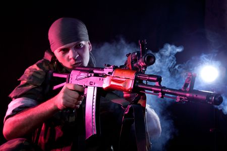 Aggressive soldier in uniform with rifle, focus on weapon  