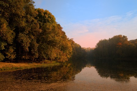 Autumn landscape with lake and fog in the forest 