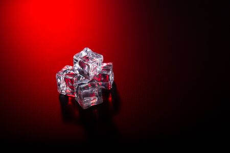 Ice cubes on black background with red club style lightの写真素材