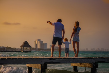 Family on the beach at sunset standing on the pierの写真素材