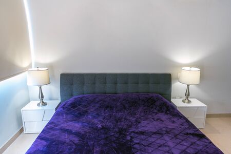 Double-bed with a violet coverlet in the interiorの写真素材