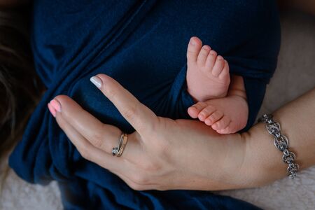 Newborn baby feet and hands of parents. Palms together.