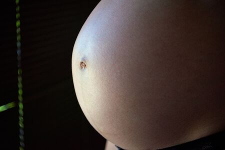 Tummy of pregnant woman in a side illuminationの写真素材