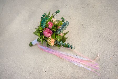 Beautiful bouquet of white, blue, pink flowers and greenery, decorated with long silk ribbon, lies on vintage wooden chairの写真素材
